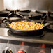 A pan of macaroni and cheese on an American Metalcraft black oval silicone trivet on a stove.