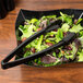 A bowl of salad with Fineline black plastic tongs.