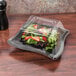 A salad in a clear plastic container with a clear dome lid.