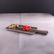 An Elite Global Solutions rectangular faux hickory wood serving board with red peppers on it.