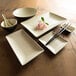 A rectangular white and ebony melamine plate on a table with chopsticks.
