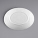 A white Elite Global Solutions oval coupe platter with a white rim on a gray surface.