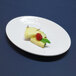 A white Elite Global Solutions oval platter with pineapple and raspberry slices on it.