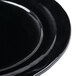 A close-up of a black Elite Global Solutions Della Terra melamine plate with an irregular round shape.