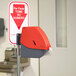 A red and grey Turn-O-Matic take a number dispenser with a sign.