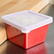 A clear polypropylene lid on a red square crock.