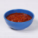 An Elite Global Solutions blue speckle bowl filled with red chili on a white table.