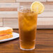 A clear GET plastic tumbler of iced tea with a lemon slice.