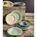An Elite Global Solutions Hemlock double-line bowl on a wooden table with plates and bowls.