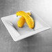 A white square melamine bowl filled with yellow squash.