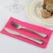 A fork and knife on a Creative Converting hot magenta pink paper dinner napkin.