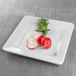 A white Elite Global Solutions square melamine plate with radishes and slices on it.