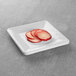 A white square Elite Global Solutions melamine plate with sliced radishes on it.