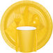 A yellow rectangle of white Creative Converting 2-ply paper dinner napkins with a yellow cup, fork, and spoon.