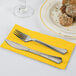 A knife and fork on a School Bus Yellow Creative Converting dinner napkin.