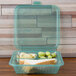 A jade GET 3-compartment take out container with grapes, bread, and a sandwich inside.