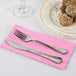 A fork and knife on a pink Creative Converting dinner napkin.