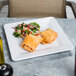 A white Elite Global Solutions Square Pebble Creek melamine plate with a burrito on it.