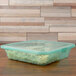 A jade green plastic GET single entree take out container with food inside.