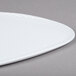 A white freestyle triangle melamine plate with a white rim on a gray surface.