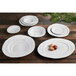 A group of white irregular oval serving dishes on a wooden table.