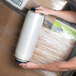 A person holding a box of Lavex pre-stretched hand pallet wrap with four rolls inside.