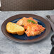 A close up of a Elite Global Solutions two-tone melamine plate with chicken and bread on it.
