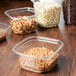 A group of 12 oz. square plastic deli containers filled with a variety of food items.