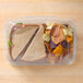 A sandwich and chips in a 10" x 7" Tamper Evident clear plastic container.