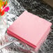 A stack of Classic Pink Creative Converting paper napkins on a table