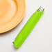 A fork and knife in a Fresh Lime green Creative Converting paper napkin.