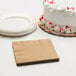 A white cake with red sprinkles next to a Creative Converting Glittering Gold beverage napkin.