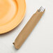 A fork and knife wrapped in a Glittering Gold Creative Converting dinner napkin.