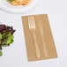 A fork and knife on a Creative Converting Glittering Gold guest towel next to a plate of salad.