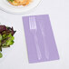 A fork and knife on a purple Creative Converting guest towel.