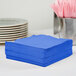 A stack of Creative Converting cobalt blue 1/4 fold luncheon napkins.