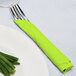 A fork and knife wrapped in a lime green napkin.