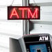 A red LED sign that says "ATM" with white letters.
