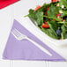 A plate of salad with strawberries and nuts on a purple Luscious Lavender napkin.