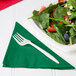 A plate of salad with strawberries, nuts, and a fork with an emerald green Creative Converting luncheon napkin.