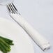 A fork and knife wrapped in a white napkin on a plate.