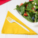 A plate of salad with strawberries, nuts, and a fork on a School Bus Yellow luncheon napkin.