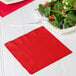 A white table set with a plate of salad and a red Classic Red luncheon napkin.
