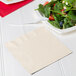 A plate of salad with a Creative Converting ivory napkin on it.