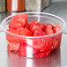 A Choice plastic deli container filled with watermelon chunks on a counter.