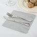 A plate of food with a knife on a Creative Converting Shimmering Silver luncheon napkin.