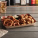 A box of fried food on a table with a red checkered paper food tray of fried chicken and fried onion rings.