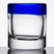 A clear Libbey shot glass with a cobalt blue rim on a table.