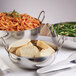An American Metalcraft stainless steel balti dish filled with pasta and bread on a table with other bowls of food.