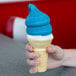 A person holding a blue ice cream cone with Phillips Blue Raspberry ice cream shell coating.
